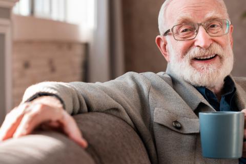Hombre anciano sonriente bebiendo una taza de café