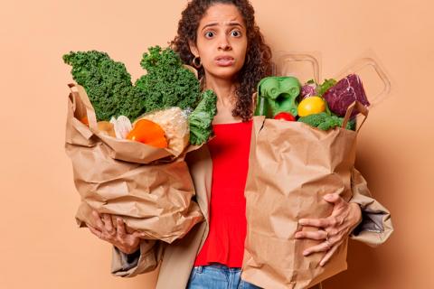 Mujer con bolsas de compra repletas de verduras y frutas