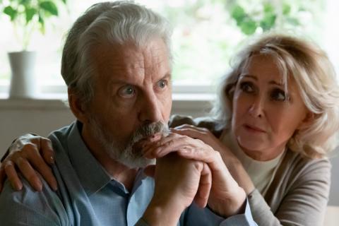 Hombre mayor con la mirada perdida junto a su mujer preocupada