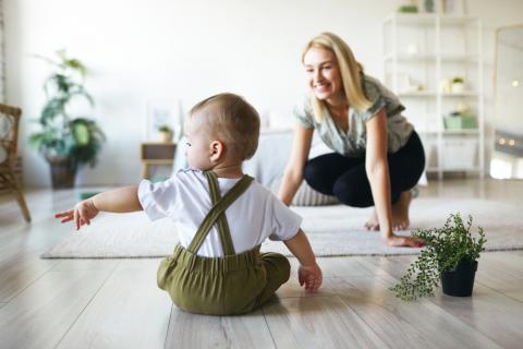 Un bebé sentado en el suelo señala algo a su madre
