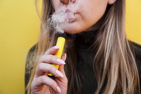 Chica rubia vapeando con su cigarrillo electrónico amarillo