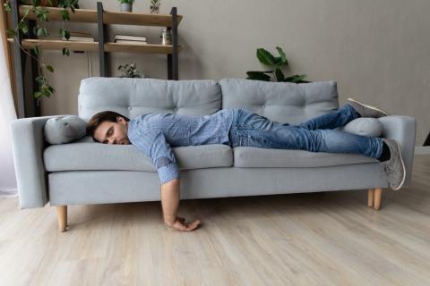 Hombre joven tumbado en el sofá echándo la siesta