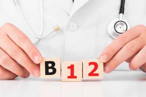 Un médico sosteniendo en las manos unos cubos de madera con las letras B12