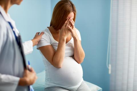 Mujer embarazada deprimida siendo consolada por el médico