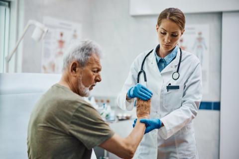 Doctor examinando a un anciano con dolor en la mano