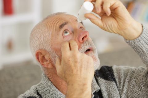 Hombre mayor usando gotas humectantes para aliviar la sequedad ocular