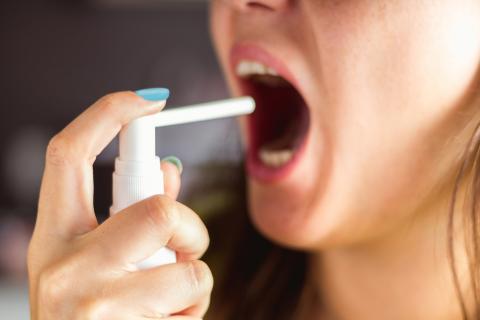 Mujer se administra una vacuna oral con un inhalador