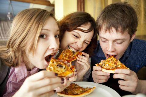 Grupo de adolescentes comiendo pizza