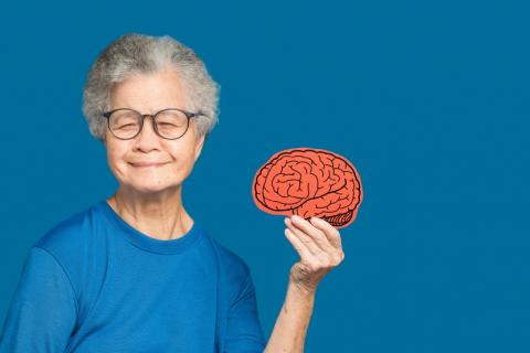 Una anciana sosteniendo en la mano un cerebro de papel