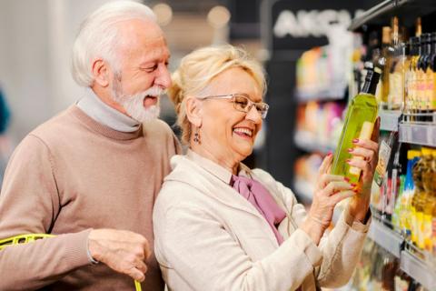 Hombre y mujer mayores examinan una botella de aceite de oliva en la tienda