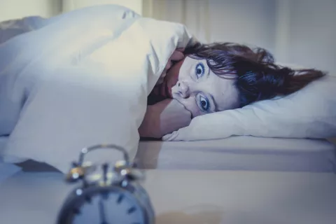 Las zonas del cerebro afectadas por los trastornos del sueño difieren en función de si son a corto o largo plazo Mujer joven con los ojos abiertos en la cama sin poder dormir