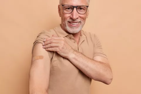 Vacunarse contra el herpes zóster puede proteger frente a patología cardiovascular Hombre mayor sonriente muestra el brazo con una tirita donde le han puesto la vacuna