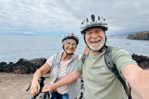 Comprueban que elevar los niveles de Klotho aumenta la esperanza de vida saludable Hombre y mujer mayores se hacen un selfie con sus bicicletas junto al mar