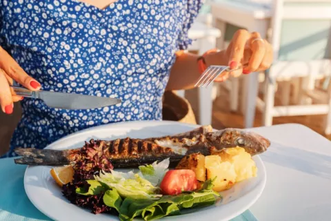 Las mujeres posmenopáusicas que siguen la dieta mediterránea tienen menos riesgo de cáncer de mama Una mujer se dispone a comer un plato de pescado y verduras
