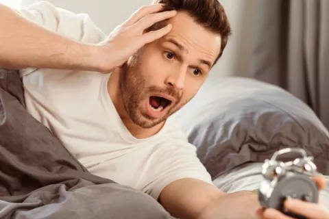 Un exceso de horas de sueño puede perjudicar la cognición y la memoria Hombre en la cama se asusta al comprobar en su despertador que ya es muy tarde