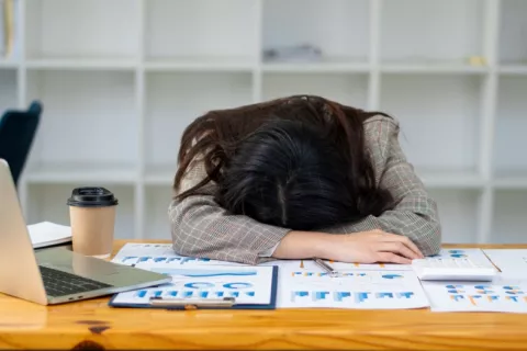 Un fármaco reduce síntomas de la narcolepsia como la somnolencia y la cataplejía Mujer dormida sobre su escritorio durante una jornada de trabajo