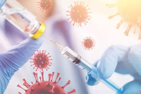 Un Acuerdo Global de la OMS ayudará a coordinar la prevención de pandemias y la respuesta si se producen Manos de un sanitario sostienen una jeringa y un vial con vacuna rodeadas por moléculas de virus