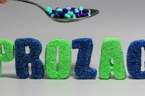 Cuchara con cápsulas sobre letras formando la palabra prozac