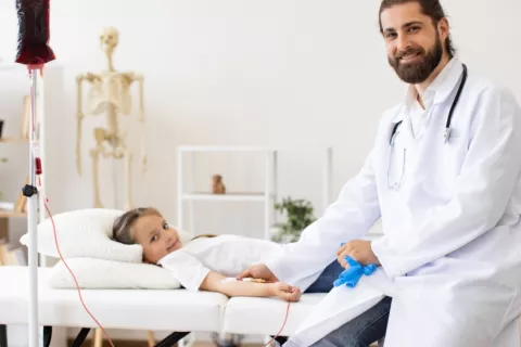 Niña recibe una transfusión sanguínea para tratar la anemia de Fanconi Una niña se dispone a recibir una transfusión de sangre junto a su doctor