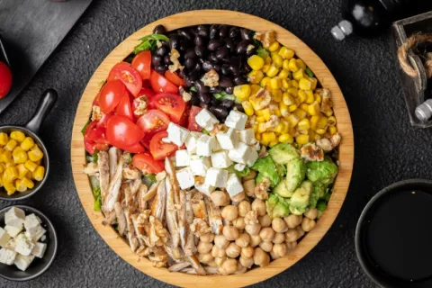 Garbanzos y frijoles negros forman parte de una ensalada Plato de ensalada con tomates, frijoles negros, garbanzos, maíz y queso