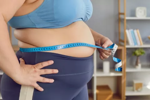 Mujer con obesidad mide su perímetro abdominal Mujer obesa utiliza cinta métrica para medir su perímetro abdominal