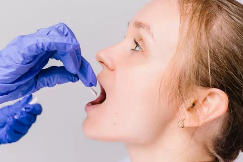 Toma de muestra de saliva para el diagnóstico de enfermedades Sanitario toma una muestra de saliva de la boca de una joven