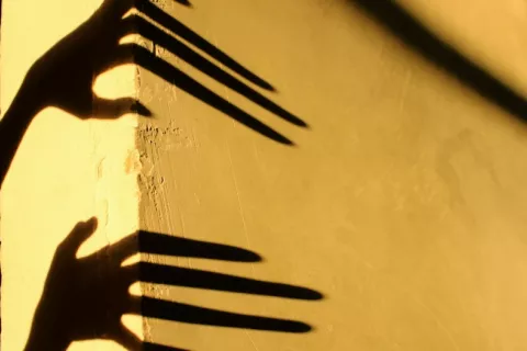 Sombra alargada de dos manos sobre una pared amarilla