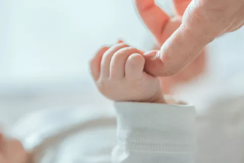 Tratamiento reduce mortalidad por neumonía en bebés con VIH Bebé cogiéndole el dedo a su madre