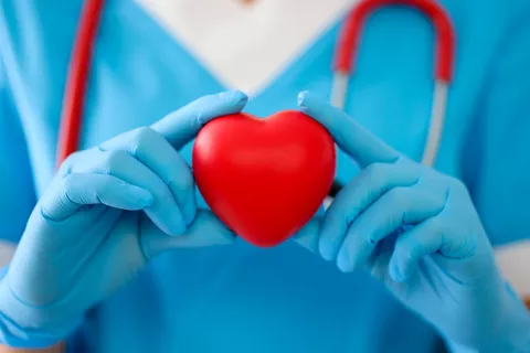 Médico sostiene un corazón rojo en sus manos