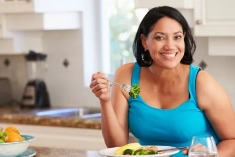 Mujer sigue una dieta saludable para perder peso Mujer con sobrepeso come de forma saludable en su cocina