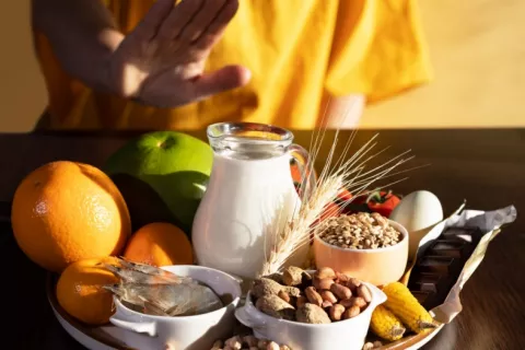 Mujer rechaza con la mano alimentos a los que tiene alergia, como pescado, marisco, lácteos, frutos secos, huevos, chocolate, trigo, soja, cítricos…