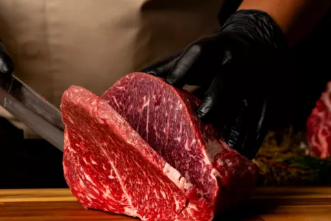 Un chef corta en filetes una pieza de carne roja