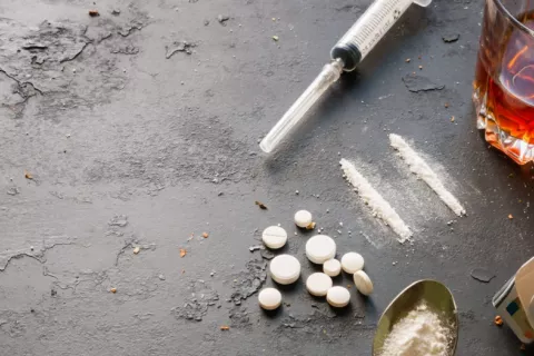Jeringuilla, vaso con wihsky, cajetilla de tabaco y drogas en pastillas y en polvo