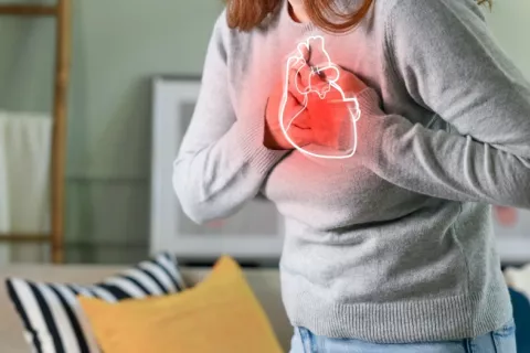 Mujer apoya sus manos sobre la ilustración de un corazón en su pecho 