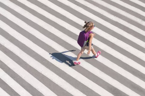 Niña acumulando pasos diarios mientras camina hacia la escuela Niña va al colegio con mochila caminando atravesando un paso de cebra