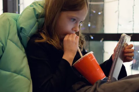 Chica mirando el teléfono en un restaurante de fast food mientras bebe un refresco