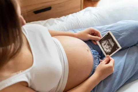 Embarazada tumbada mirando la ecografía de su futuro bebé