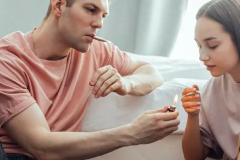 Hombre y mujer jóvenes se disponen a fumar cannabis