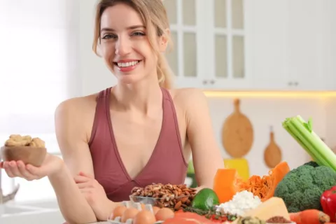 Mujer joven sonríe en su cocina junto a alimentos saludables