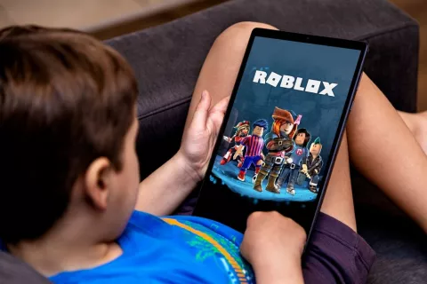 Un menor tumbado jugando a Roblox en su tablet