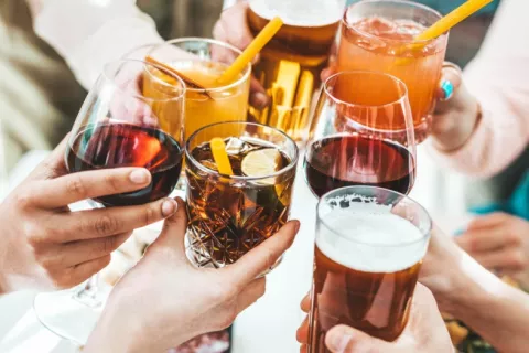 Varias personas brindan con distintos tipos de bebidas alcohólicas