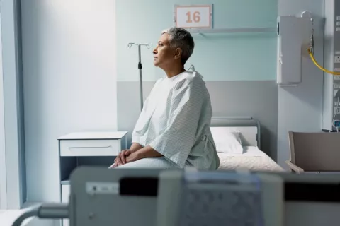 Mujer madura mira por la ventana sentada en la cama de un hospital