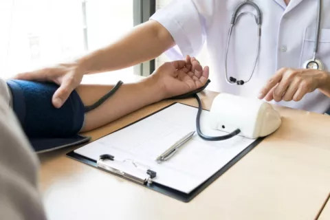 Doctor toma la tensión a un paciente en consulta