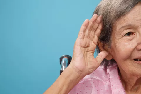 Mujer anciana con la mano en la oreja mostrando dificultades para oír