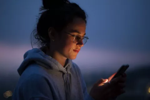 Una joven mira su smartphone al anochecer
