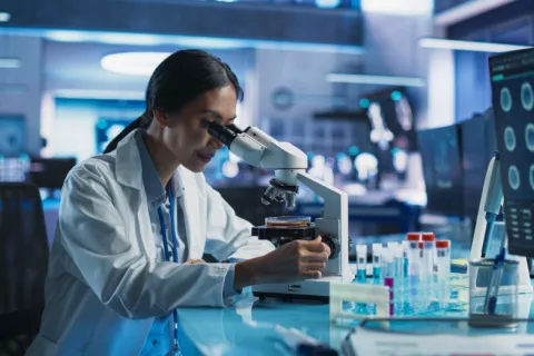 Científica mira por microscopio en su laboratorio