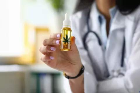 Una doctora muestra un frasco con con gotero de aceite de concentrado de cannabis