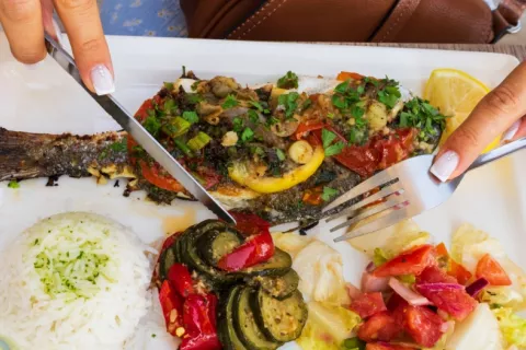Manos de mujer cortan alimentos de un menú típico de la dieta mediterránea