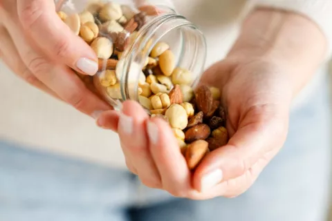 Manos de mujer sostienen un tarro de cristal con frutos secos