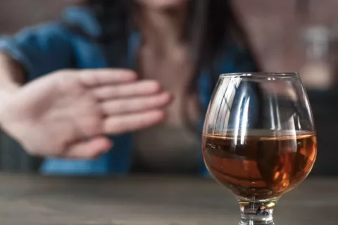 Mujer hace un gesto de rechazo con la mano a una copa de alcohol
